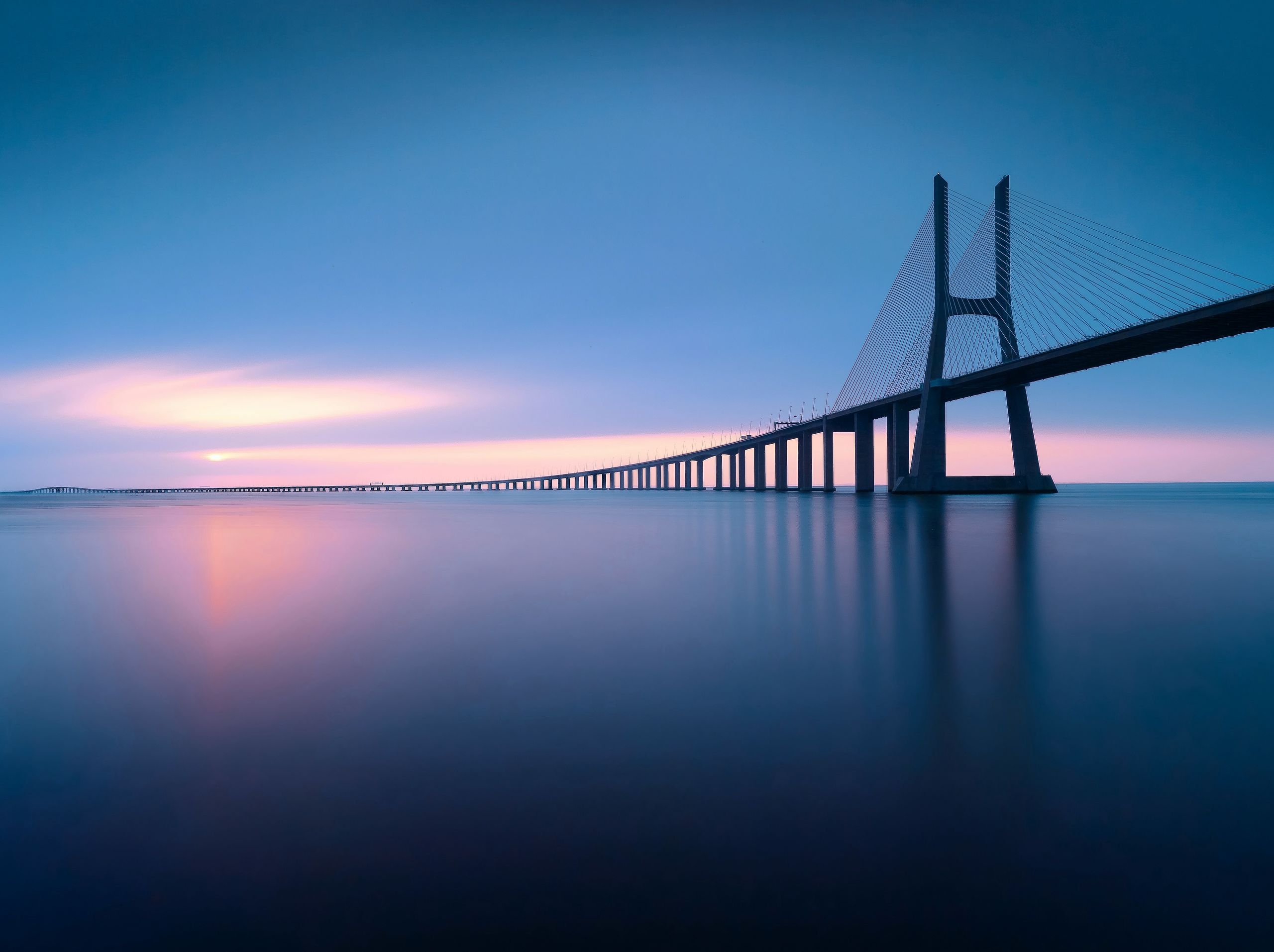 The Vasco da Gama bridge over still water at dusk
